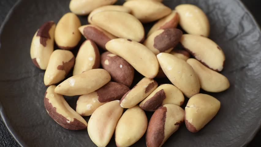 Brazil nut kernels in ceramic bowl on dark concrete background