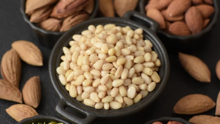 Peeled pine nuts in a bowl on a dark concrete background. Nuts as a source of protein