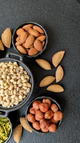 Peeled pine nuts in a bowl on a dark concrete background. Nuts as a source of protein