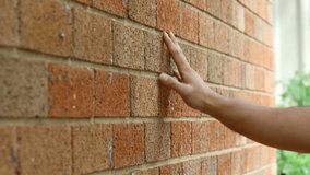 Close-up shot of a hand touching a red brick wall - Powered by Shutterstock - Get 15% off with code: PIKWIZARD15