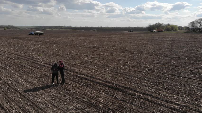 Farmer Checking His Field While Tractor Sows Sunflower Seeds