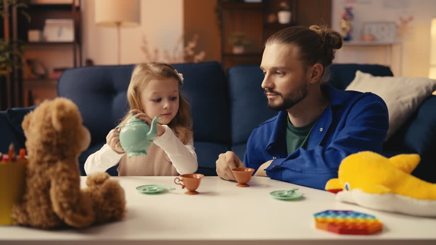 Little daughter and her dad playing tea party at home, enjoying family moment
