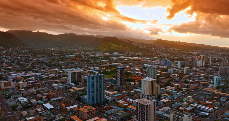 Jaw-dropping orange cloudy sky above the cityscape of Honolulu, Hawaii, USA. Splendid scenery of the city at sunset. Aerial view.