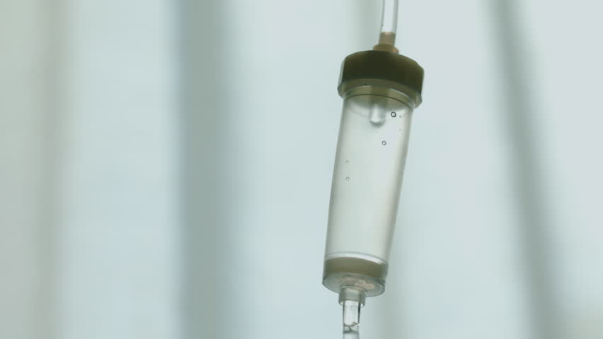 Close-up of an intravenous drip chamber with liquid drops, symbolizing medical care and recovery. High quality 4k footage
