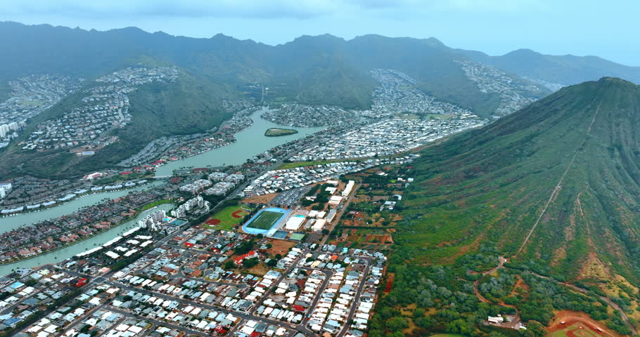 Dense rows of private houses scattered by the valley among the mountains and their slopes. Scenic view of Honolulu, Hawaii, USA. Aerial perspective.