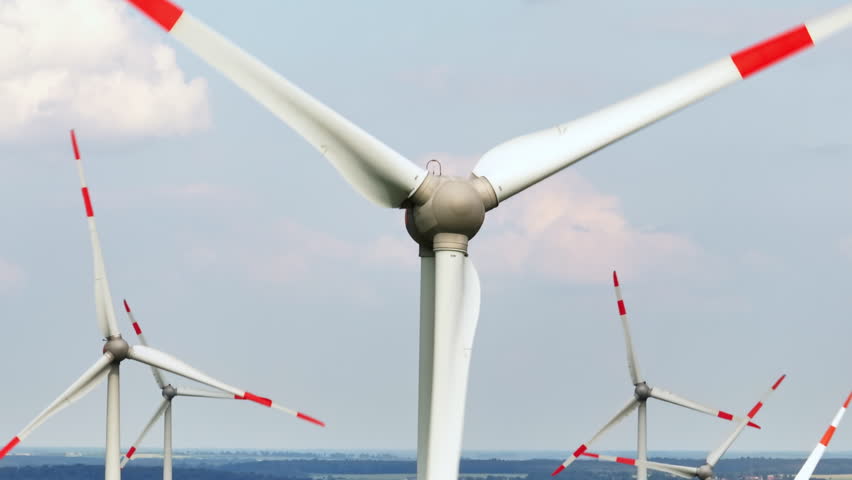Aerial close-up shot circling a wind turbine at a eolic energy farm, sunny day
