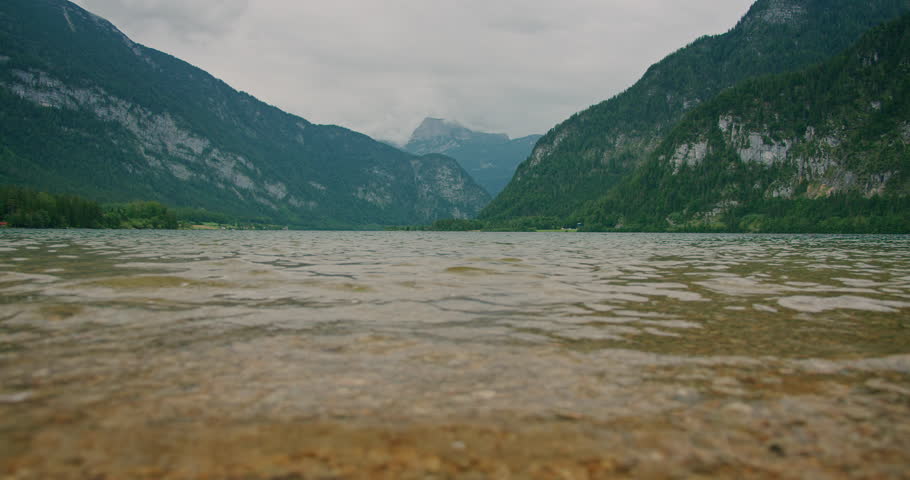 Low-angle view of an alpine lake Gosausee with a rocky shore and misty mountains in the background