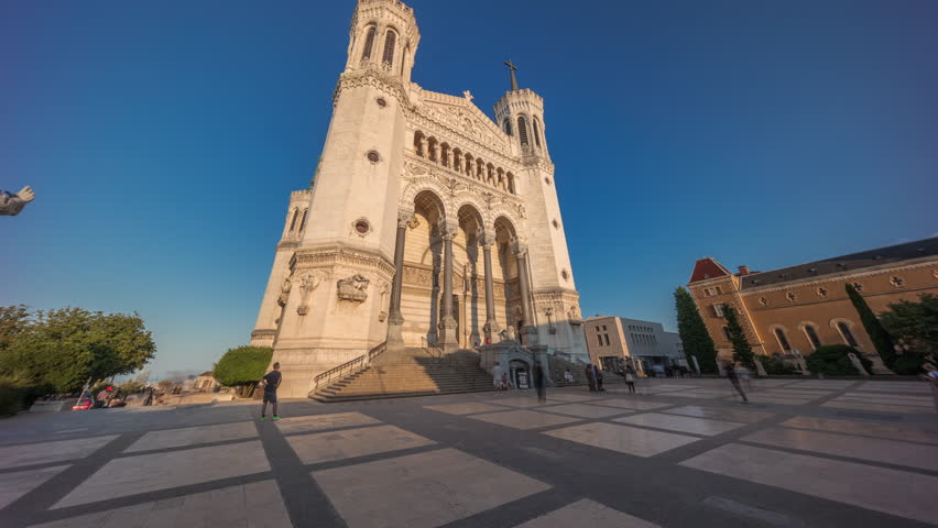 Hyperlapse front view of the Basilica of Notre Dame de Fourviere during sunset in Lyon, France. This iconic minor basilica is illuminated with warm light, overlooking the city from a hilltop timelapse