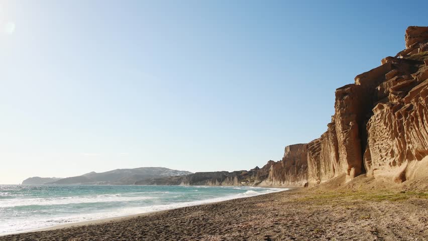 Santorini island, Greece. Yellow pumice volcanic cliffs on Vlichada beach. Blue sea and the blue sky at sunset. Summer landscape
