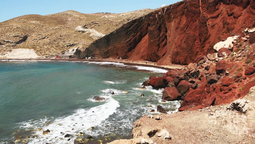 Red beach in Santorini island, Greece. Red volcanic pumice cliffs with black sand on the beach. Blue sea and the blue sky at sunny day. Beautiful summer seascape
