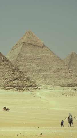 Tourists and Egyptians on camels moving to famous Great Pyramid of Giza, travel and tourism, vertical video with historical and architectural landmark, culture of ancient Egypt and history of mankind