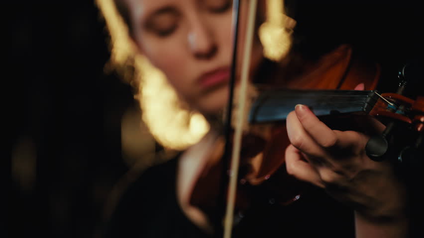 Cinematic closeup portrait of beautiful violinist woman performing music in rain . Self-expression and express emotions and feelings, romantic love song, pretty caucasian lady playing violin, solo