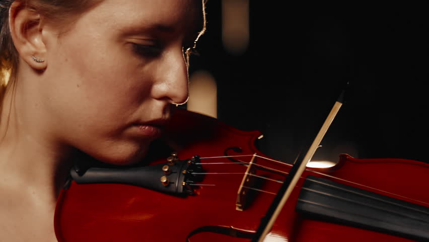 Female beauty and classical music, close up portrait of woman playing violin. Attractive female violinist performing amazing fabulous song, moving viola bow near face, emotional lady creating music