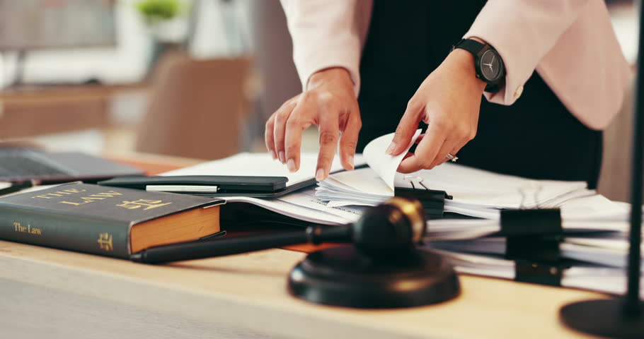 Person, hands or lawyer with paperwork for legal advice, testimonial or statements at office desk. Closeup, judge or attorney with documents or gavel for lawsuit, regulation or case notes at law firm