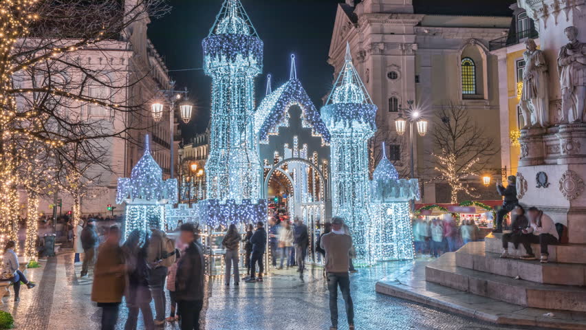 Night timelapse hyperlapse of Christmas decorations with illuminated castle on Luis de Camoes square in Lisbon, Portugal. People walking around the festive lights and historic architecture.