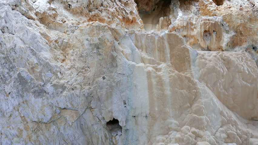 Hot spring water flowing down the wall of the karst cave. Limestone cave.