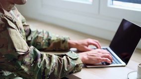 Uniformed military professional working remotely, typing on laptop while sitting at desk, embodying modern digital workplace connectivity and military adaptability - Powered by Shutterstock - Get 15% off with code: PIKWIZARD15
