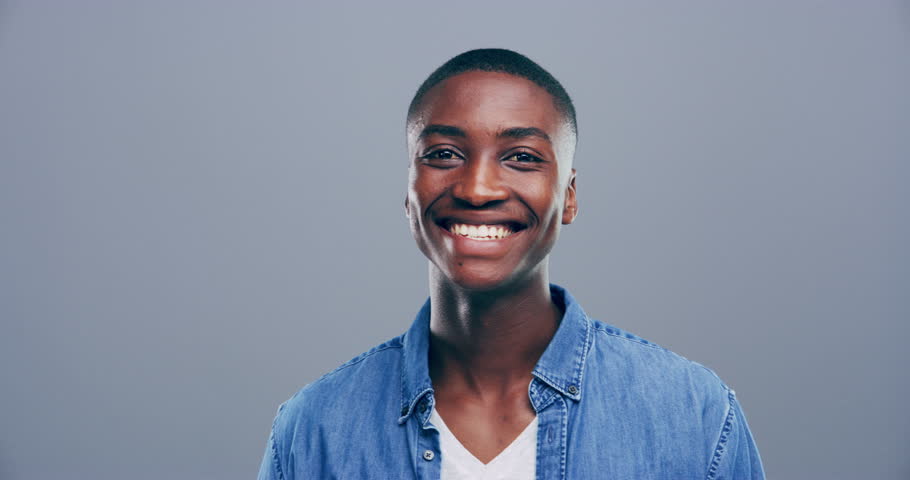 Hands, heart and face of man in studio for care, kindness or donate to charity on grey background. Portrait, smile and african model show emoji for love, vote or thank you for support, hope and peace