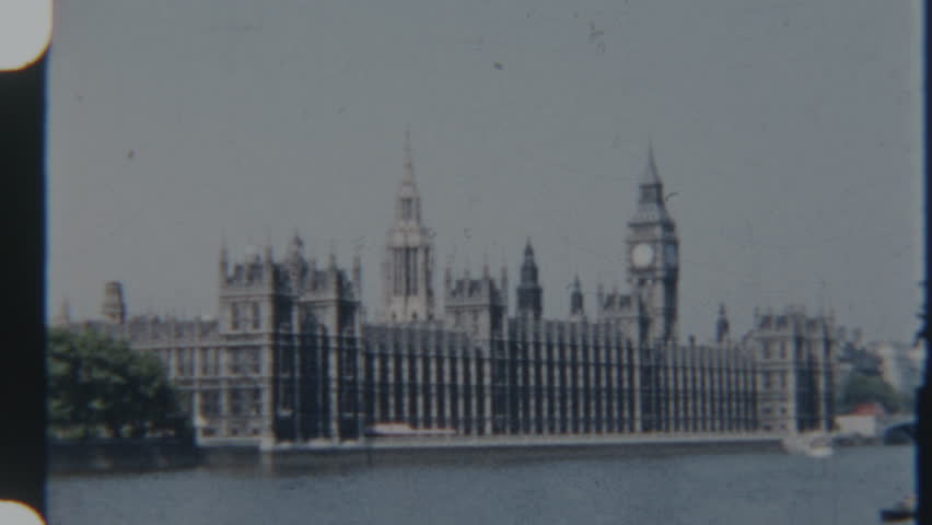 A vintage 8mm film frame from 1960s London captures a picturesque view of the Houses of Parliament and Big Ben standing majestically along the River Thames