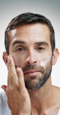 Mature man, face or skincare with cosmetics in studio for facial treatment on a white background. Portrait, male person or model applying moisturizer with cream, lotion or protection for smooth skin
