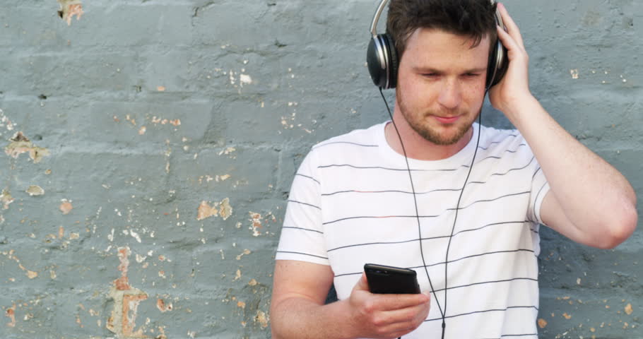 Man, headphones and music or dancing, phone and streaming audio or radio, song and podcast. Male person, listening and chilling to playlist, technology and subscription or freedom, energy and fun