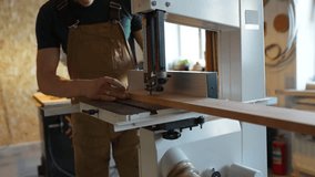 Unrecognizable craftsman working with wood bars on band saw machine in carpentry shop. Vertical tool for straight angled curved cuts and 45 degree slicing, joiner work on precision, furniture making - Powered by Shutterstock - Get 15% off with code: PIKWIZARD15