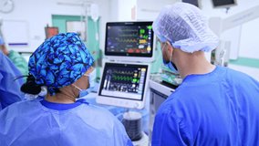 Docs track patient data in surgery. Two healthcare workers examine vital signs on monitoring equipment during a surgical procedure in a clinical setting. - Powered by Shutterstock - Get 15% off with code: PIKWIZARD15