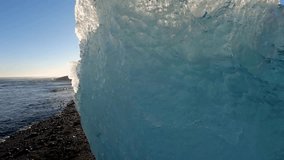 A woman stands on Diamond Beach in Iceland, gazing at the ocean with icebergs in the foreground, bathed in sunlight - Powered by Shutterstock - Get 15% off with code: PIKWIZARD15