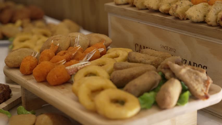 Mixed fried snacks including onion rings and shrimp on a wooden serving tray