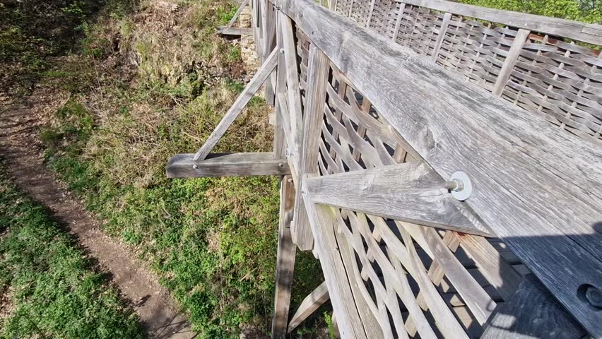Medieval oak wood, bolted. Bridge over the moat. the railing is made of massive beams, between which several thin oak rods are woven between the vertical warp. Zigzag like knitting a wicker basket.