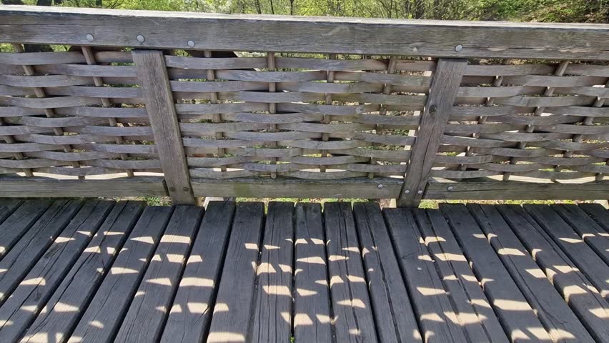 Medieval oak wood, bolted. Bridge over the moat. the railing is made of massive beams, between which several thin oak rods are woven between the vertical warp. Zigzag like knitting a wicker basket.