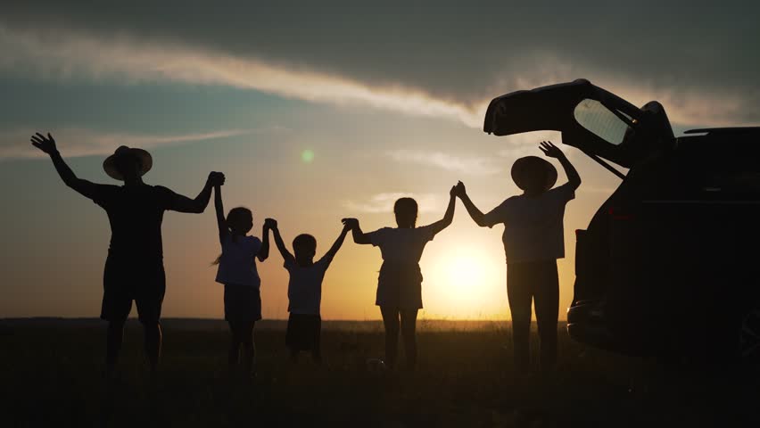 Family team standing by car at sunset. Family unity silhouette. Team family members holding hands enjoying evening. family bonding near car at sunset. Silhouette team unity. travel in unity at sunset.