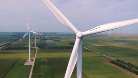 Wind Turbine Spinning Smoothly at Wind Farm - Drone Point Of View. Wind turbines rotates in agricultural landscape. Investing in renewable energy projects. Wind turbines producing electricity. - Powered by Shutterstock - Get 15% off with code: PIKWIZARD15