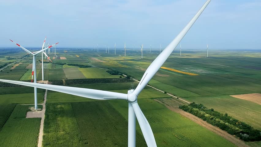 Wind Farm - Drone Point of View. Wind turbine rotates by wind in picturesque agricultural landscape. Investing in renewable energy projects. Wind turbines producing electricity.
