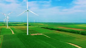 Investing in Renewable Energy Projects - Wind Turbines Producing Electricity. Drone ascending from green agricultural field to the blue sky revealing tall wind turbines rotating by wind. Green Energy. - Powered by Shutterstock - Get 15% off with code: PIKWIZARD15