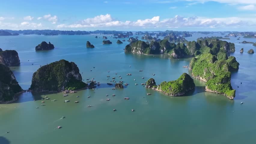 A breathtaking drone view captures Halong Bay’s emerald waters and towering limestone islands, with scattered boats adding life to this stunning natural seascape in northern Vietnam.
