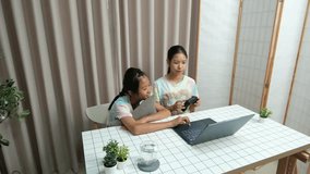 Two young Asian children playing online games after finishing homework - Powered by Shutterstock - Get 15% off with code: PIKWIZARD15