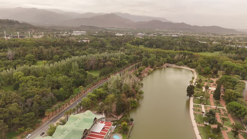Parque General San Martin lake, hazy mountains in background, cloudy day, Mendoza in Argentina. Aerial drone panoramic view