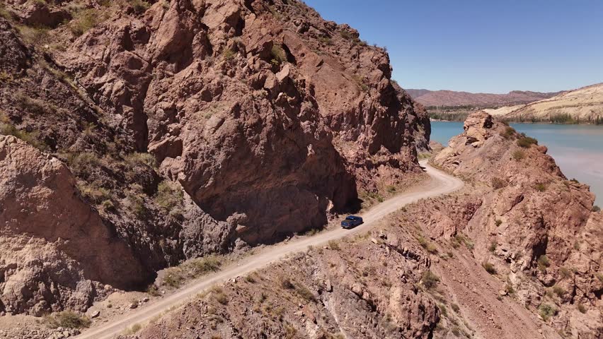 Vehicle four-wheel drive dirt road along Potrerillos lake, arid mountains background, adventure travel, road trip, Mendoza, Argentina,