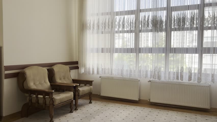 Lobby or common area with a large window, sheer curtains, and comfortable seating for guests or students.