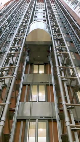 Modern passenger elevator made of metal and glass in the main hall of the new business center. Loaded elevator with people goes down