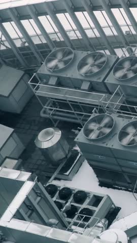 A lot of air conditioning unit fan spinning on roof of industrial building in American city. View from above