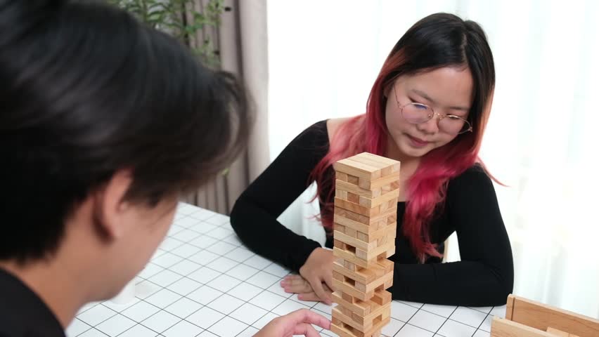Happy couple playing wooden games together in cozy living room at home