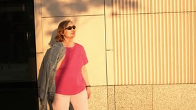 Happy senior woman in pink t-shirt in sunglasses walking and standing behind sunny wall in summer - Powered by Shutterstock - Get 15% off with code: PIKWIZARD15