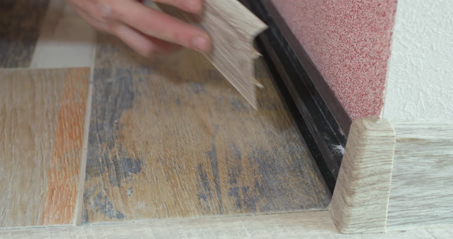 Corner connection of the skirting board. A man installs a plastic skirting board on the floor of an apartment.