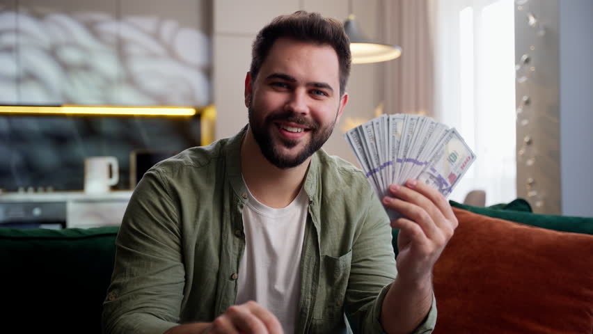 Smiling happy Caucasian business man male guy homeowner businessman showing house apartment key keychain holding money cash dollars selling real estate housing mortgage buying new home in living room