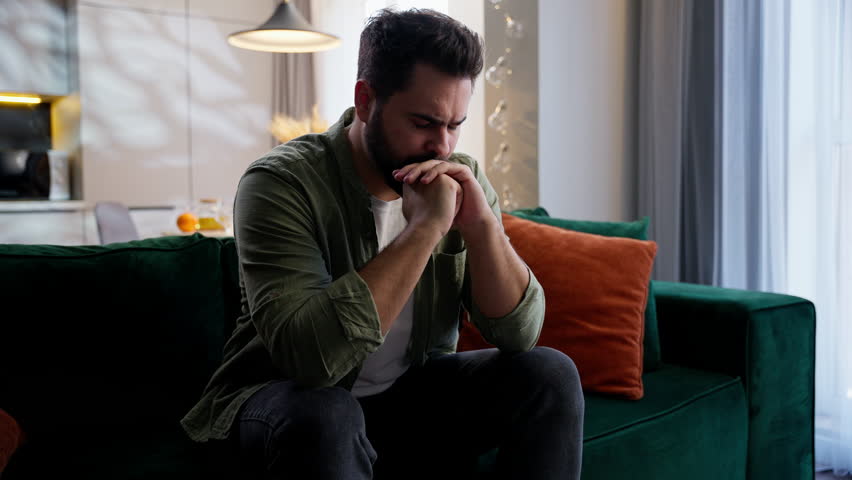 Stressed sick unhappy Caucasian man business male businessman guy homeowner unwell troubled buyer client customer sitting couch covering face with hands stress gesture problems headache pain at home