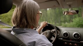 Back view happy smiling Caucasian aged elderly female cheerful mature senior woman taxi car driver riding in automobile driving auto steering wheel stop vehicle turning looking camera passenger smile - Powered by Shutterstock - Get 15% off with code: PIKWIZARD15