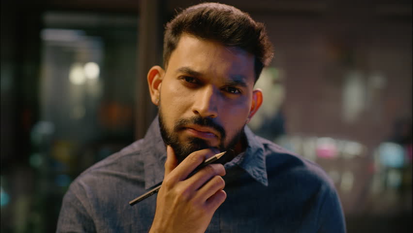 Thoughtful thinking Indian man guy think businessman working at night evening office Arabian male business employer manager analyst writing notes consider task ideas planning create write in notebook