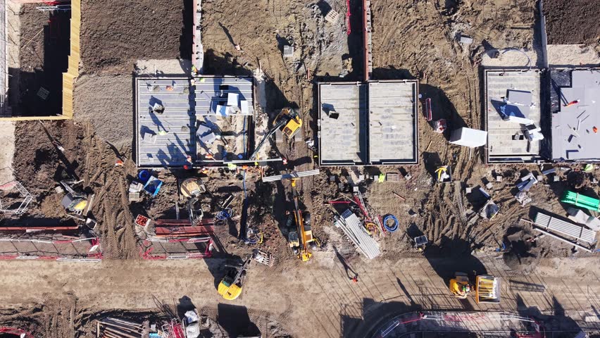 Aerial view of construction site showing workers, machinery, and structures being developed in rural area during daylight hours